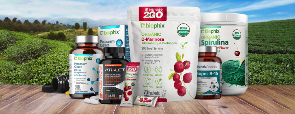 Health supplement products on a table in front of a field of vegetables.