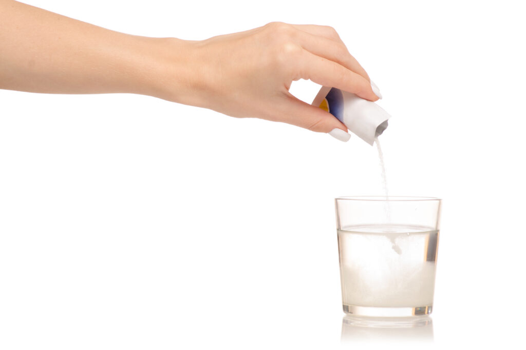 Female hand pouring in hydration powder into water