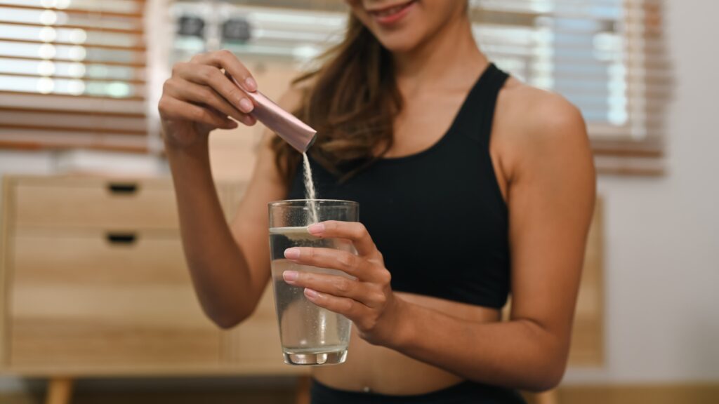 Female athlete pouring in a hydration powder after a workout