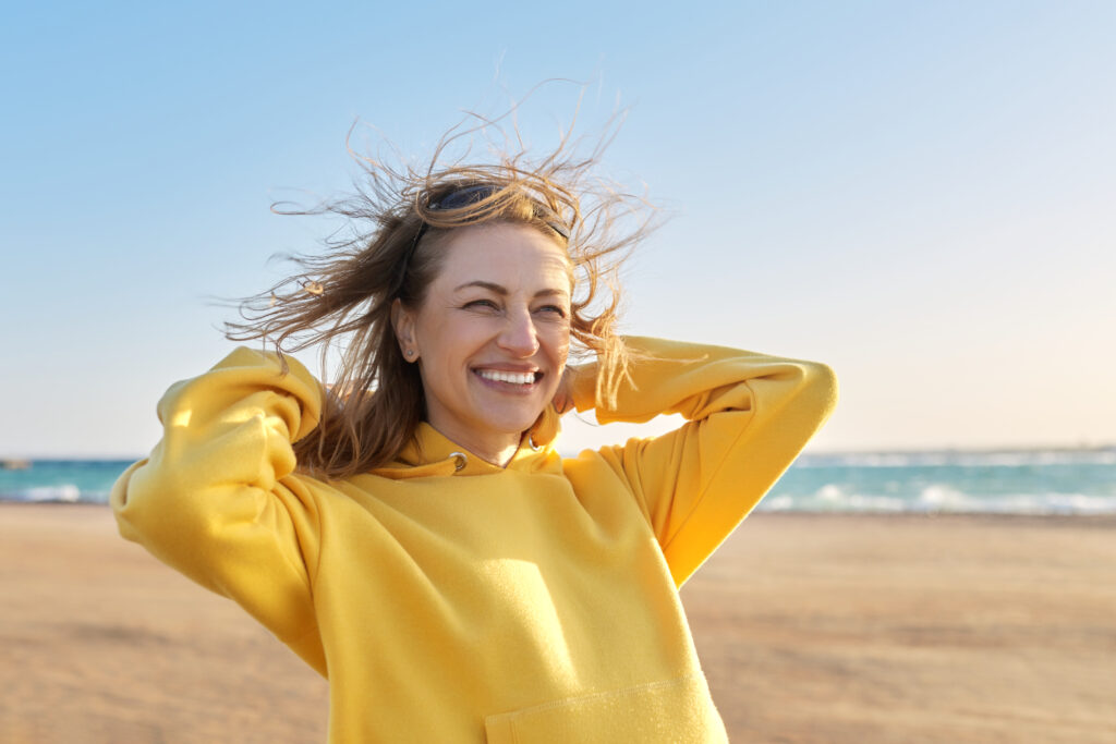 Midlife woman smiling on the beach.