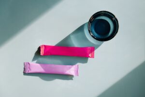 Stick pack health supplements on a table with a glass of water