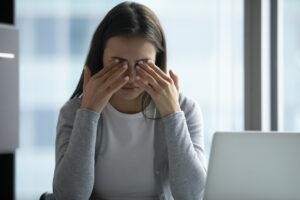 Woman experiencing digital eye strain at a laptop representing the growing demand for vision health supplements